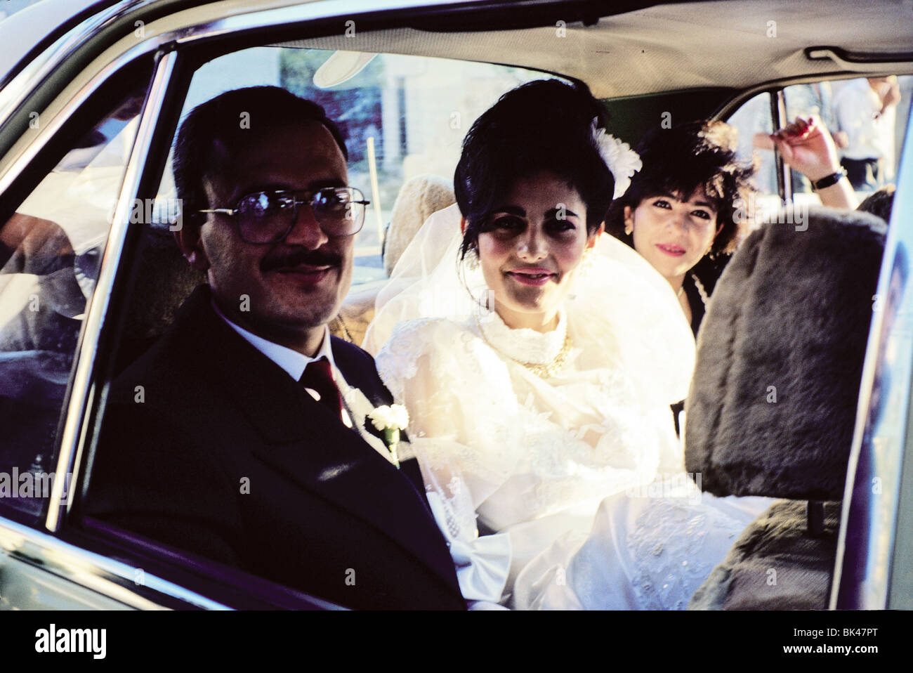 Jordanian bride wearing a white wedding dress with her attendants in the backseat of a car, Amman, Jordan Stock Photo