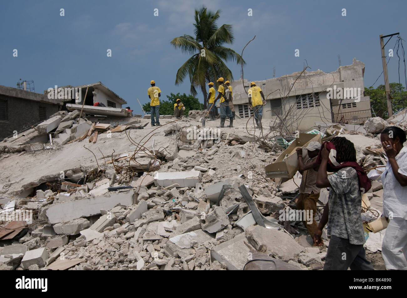 Pedestrians walk past a building that collapsed after a 7.0 magnitude ...