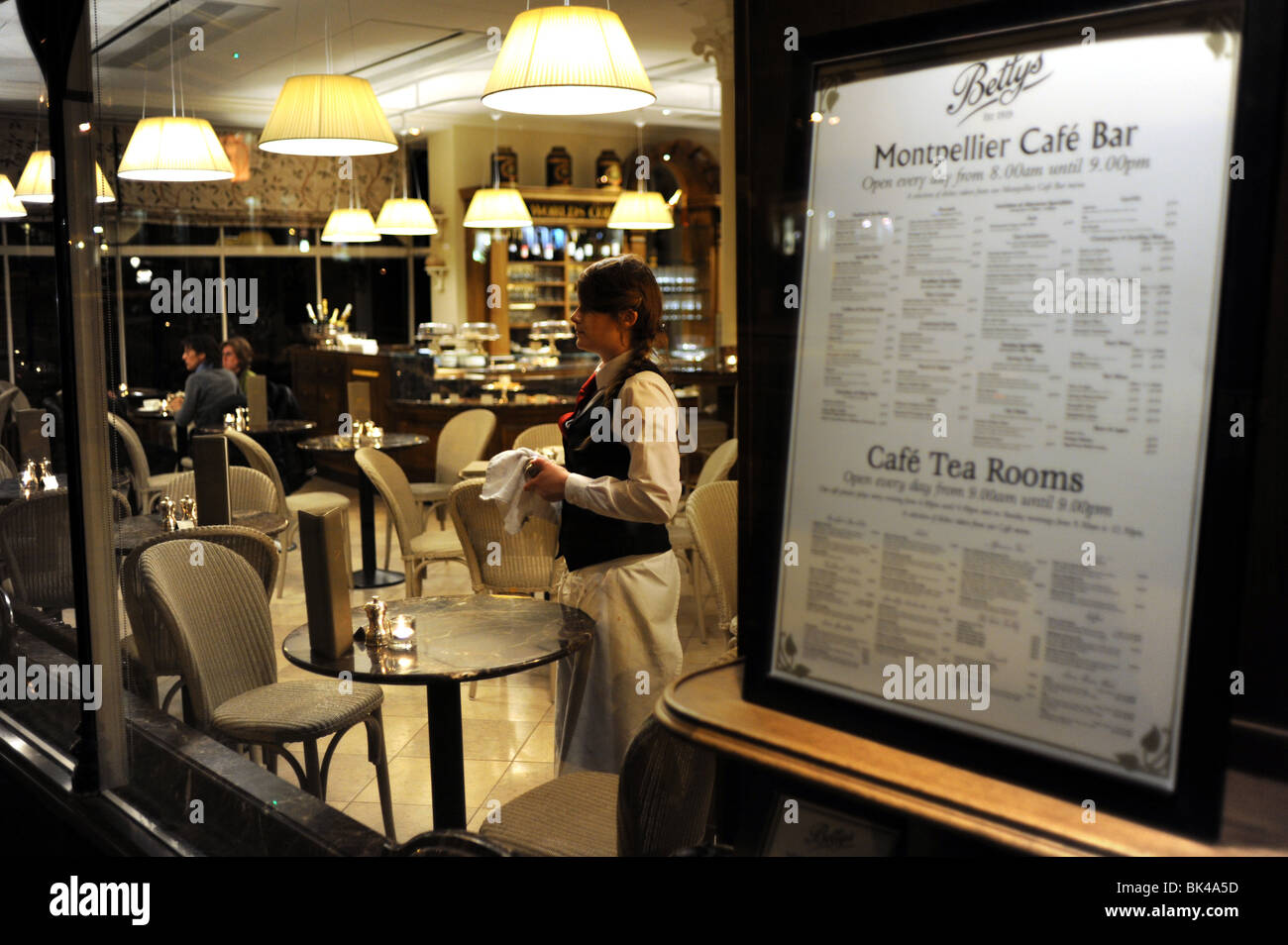A member of staff looking out the window of Bettys Cafe and Tea Rooms in Harrogate Yorkshire UK Stock Photo