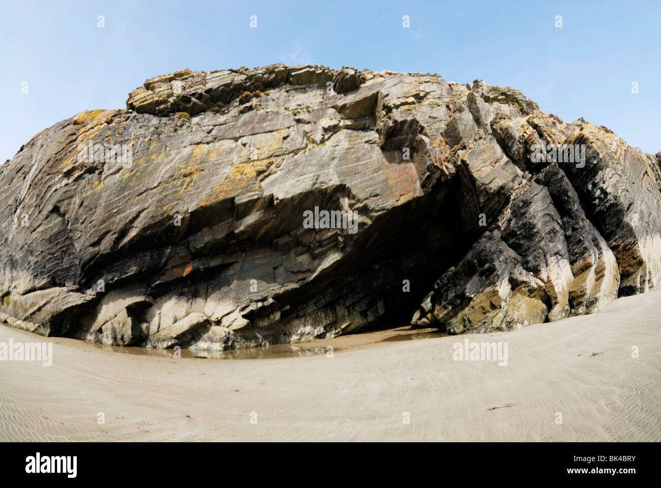 Sea cliff with caves formed by erosion of softer rock layers Stock