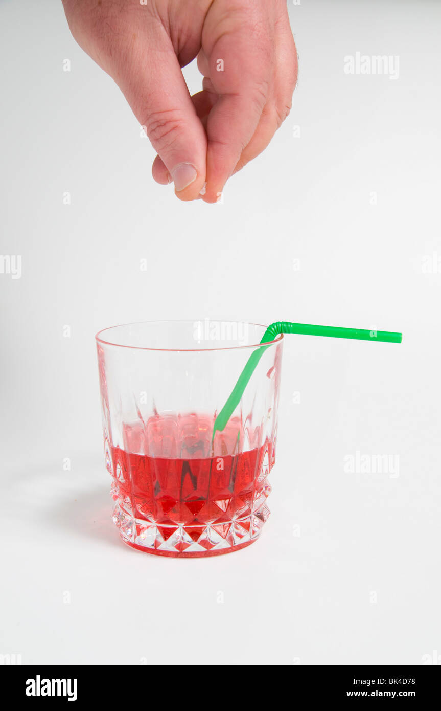 Conceptual image of a male hand adding Date rape drug (GHB gamma-hydroxybutyric acid) to a cocktail. Stock Photo