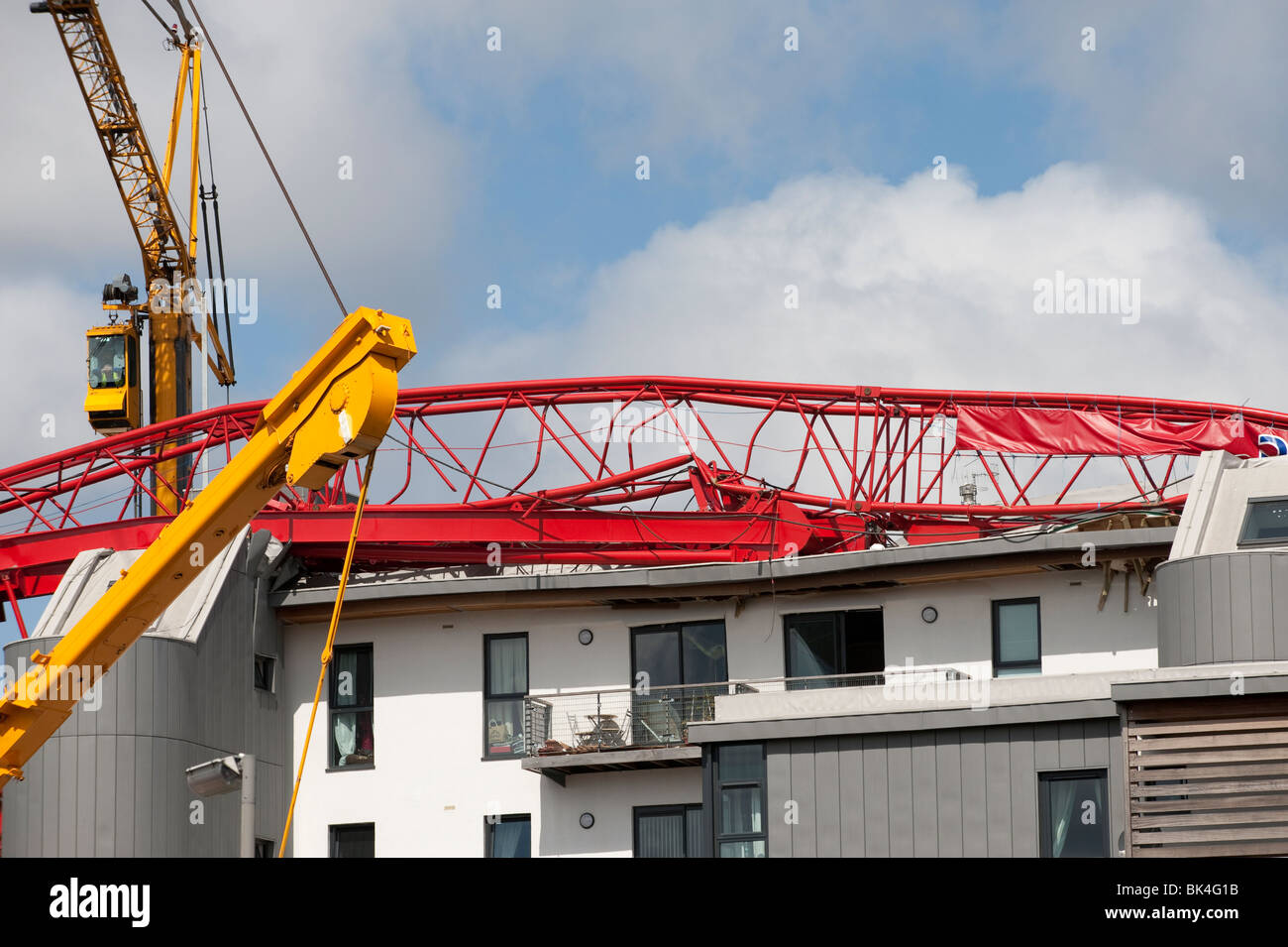 Tower crane collapsed fallen onto roof of apartment block being lifted off by another crane Stock Photo