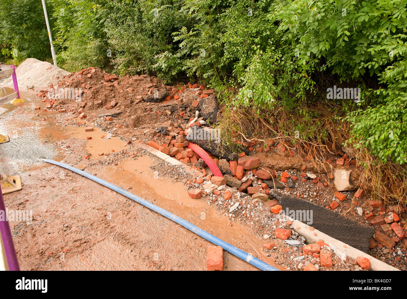 Burst water main pipe washed road and pavement away Stock Photo