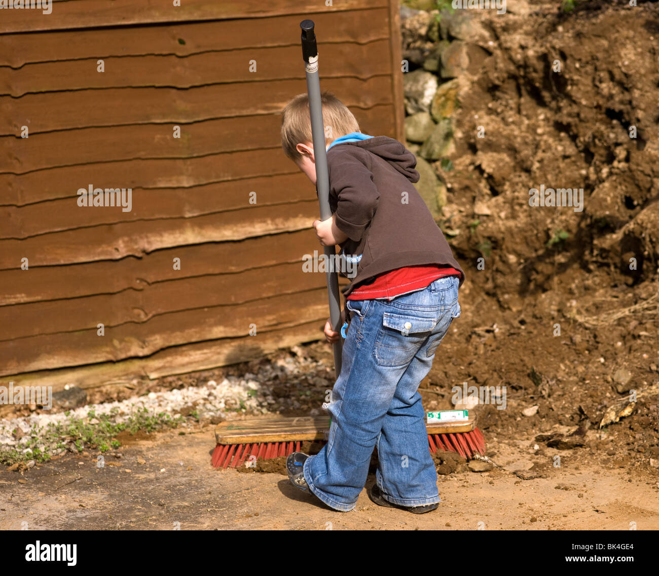 young boy sweeping dirt away in the garden Stock Photo Alamy