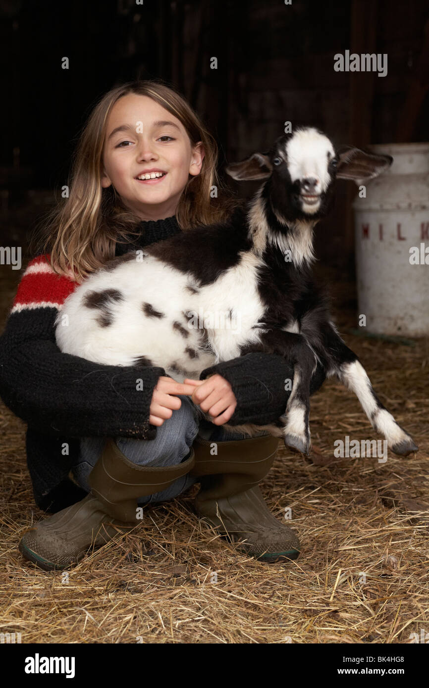 Girl in the barn laughing with her baby goat Stock Photo