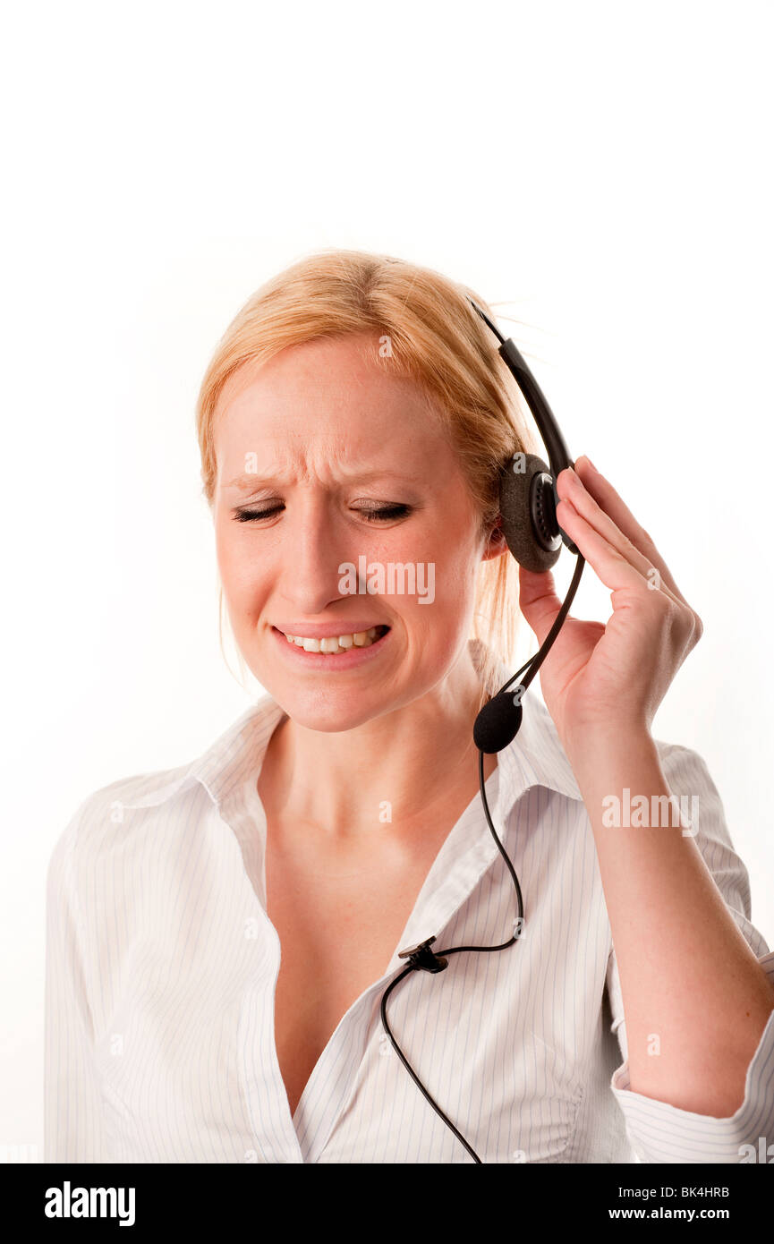 Blonde female Customer Services Telesales person wearing a telephone headset discomfort and noise pain  FULLY MODEL RELEASED Stock Photo