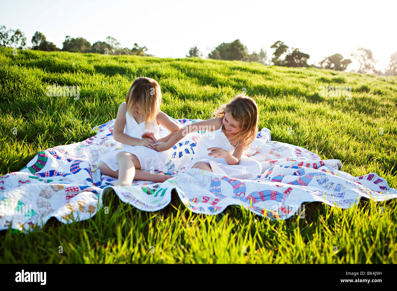 Girls on picnic blanket tickling each other Stock Photo