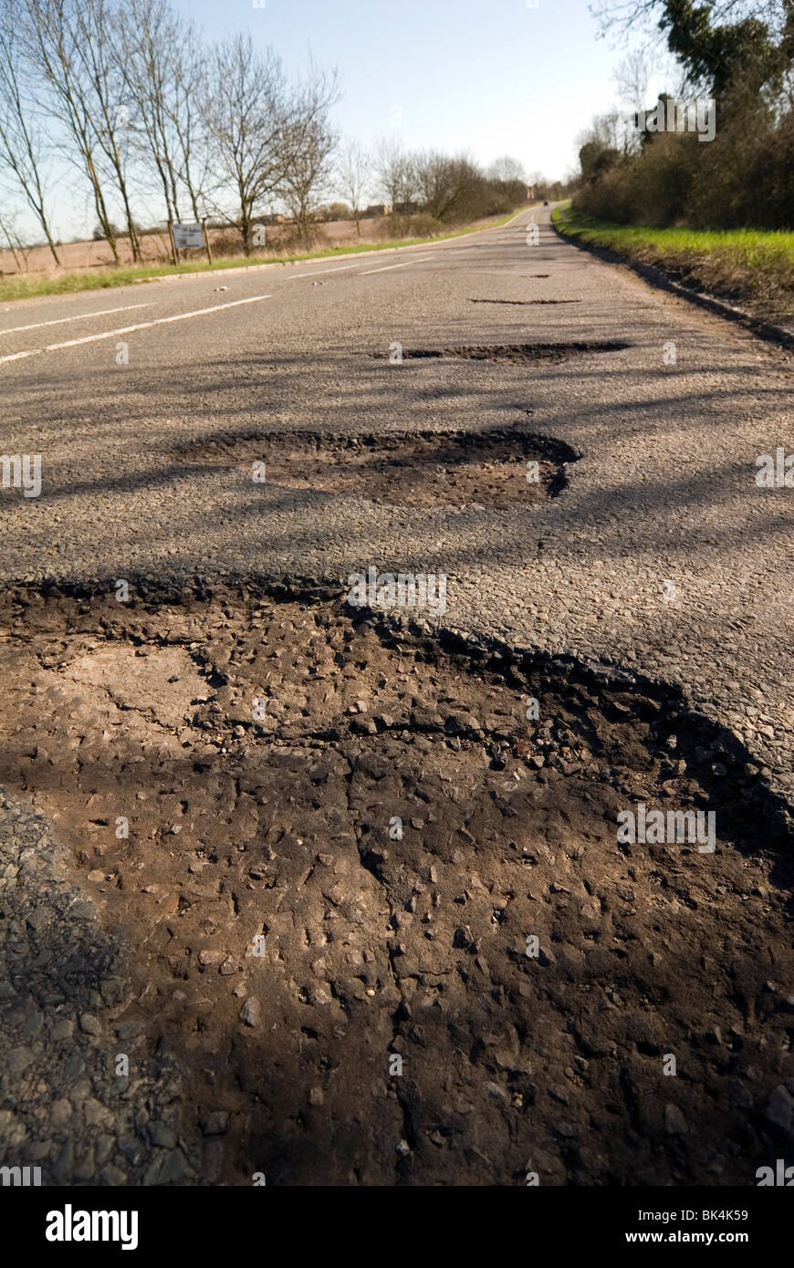 potholes in the middle of the road after a hard winter of snow. Who will pay for these pot holes to be repaired? Stock Photo