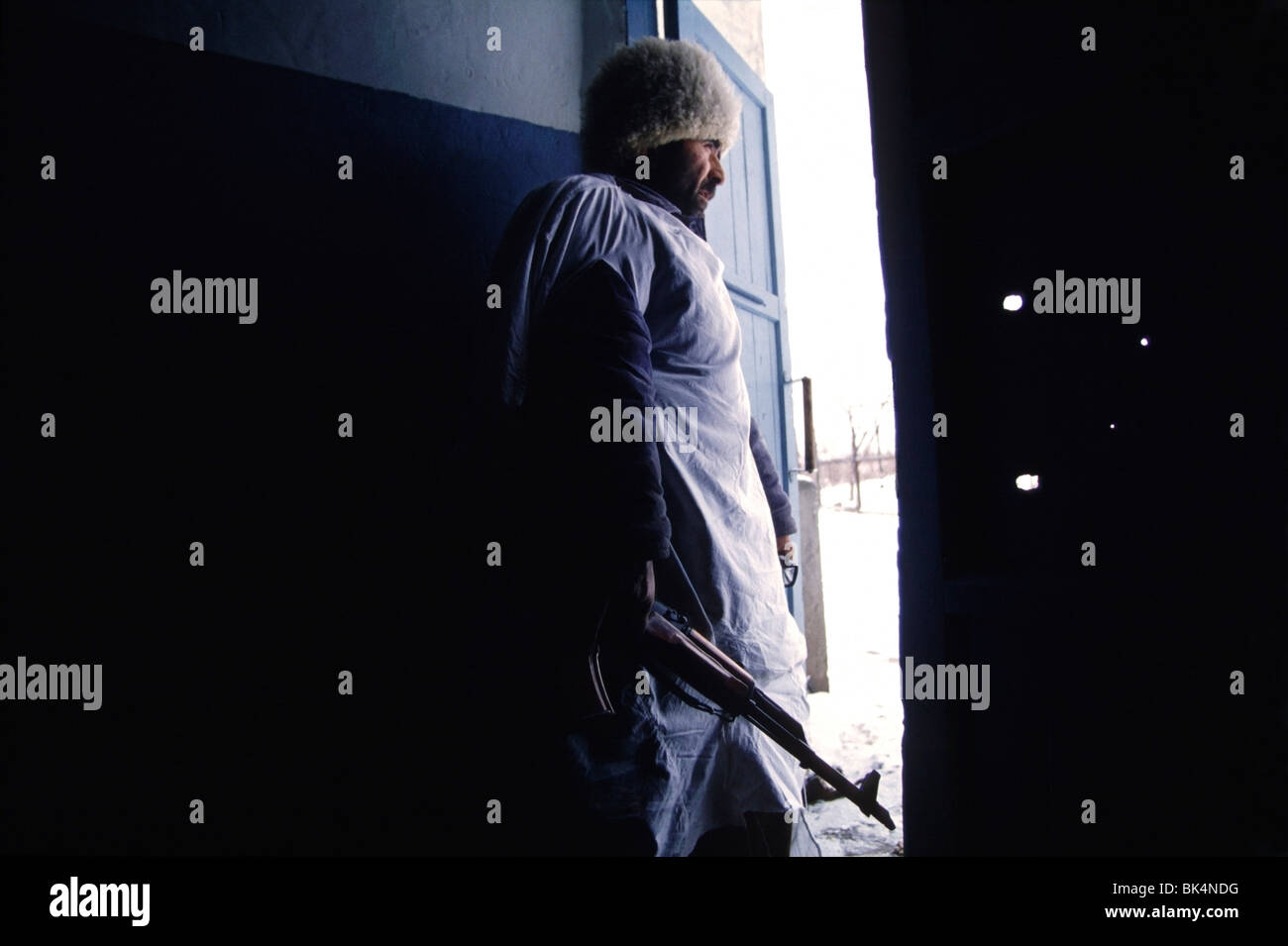 First Chechen War, Armed Chechen fighter looks out the door of an apartment building South of Grozny in Chechnya. Stock Photo