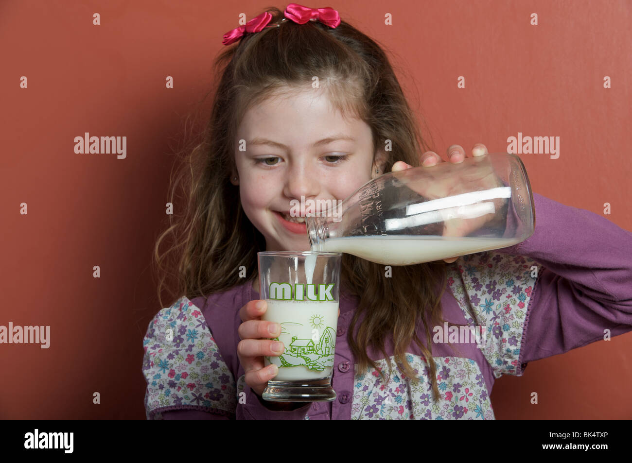 Young girl pouring a glass of milk, UK. Stock Photo