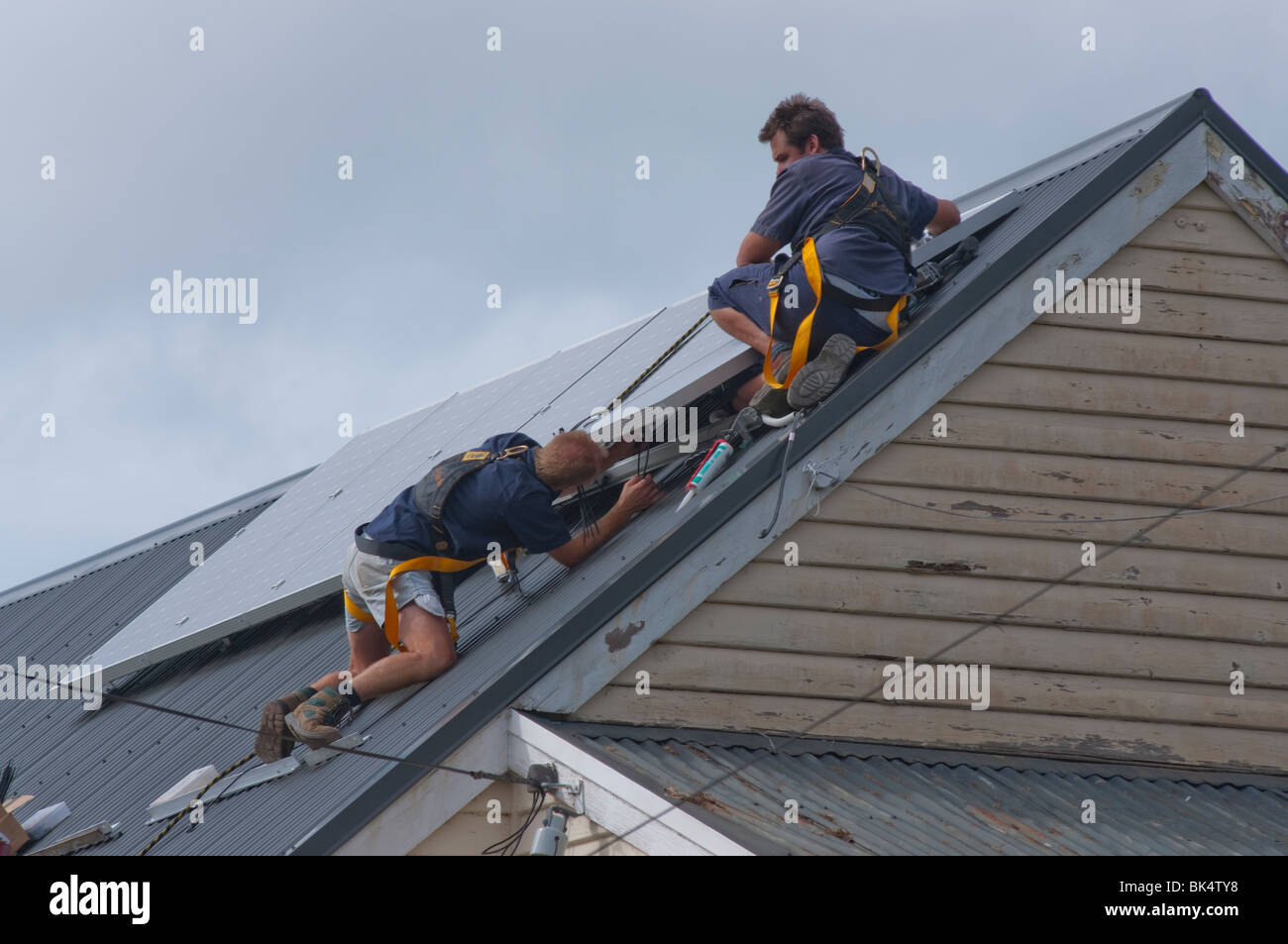 Workmen installing solar panels on roof in Hobart Tasmania Australia Stock Photo