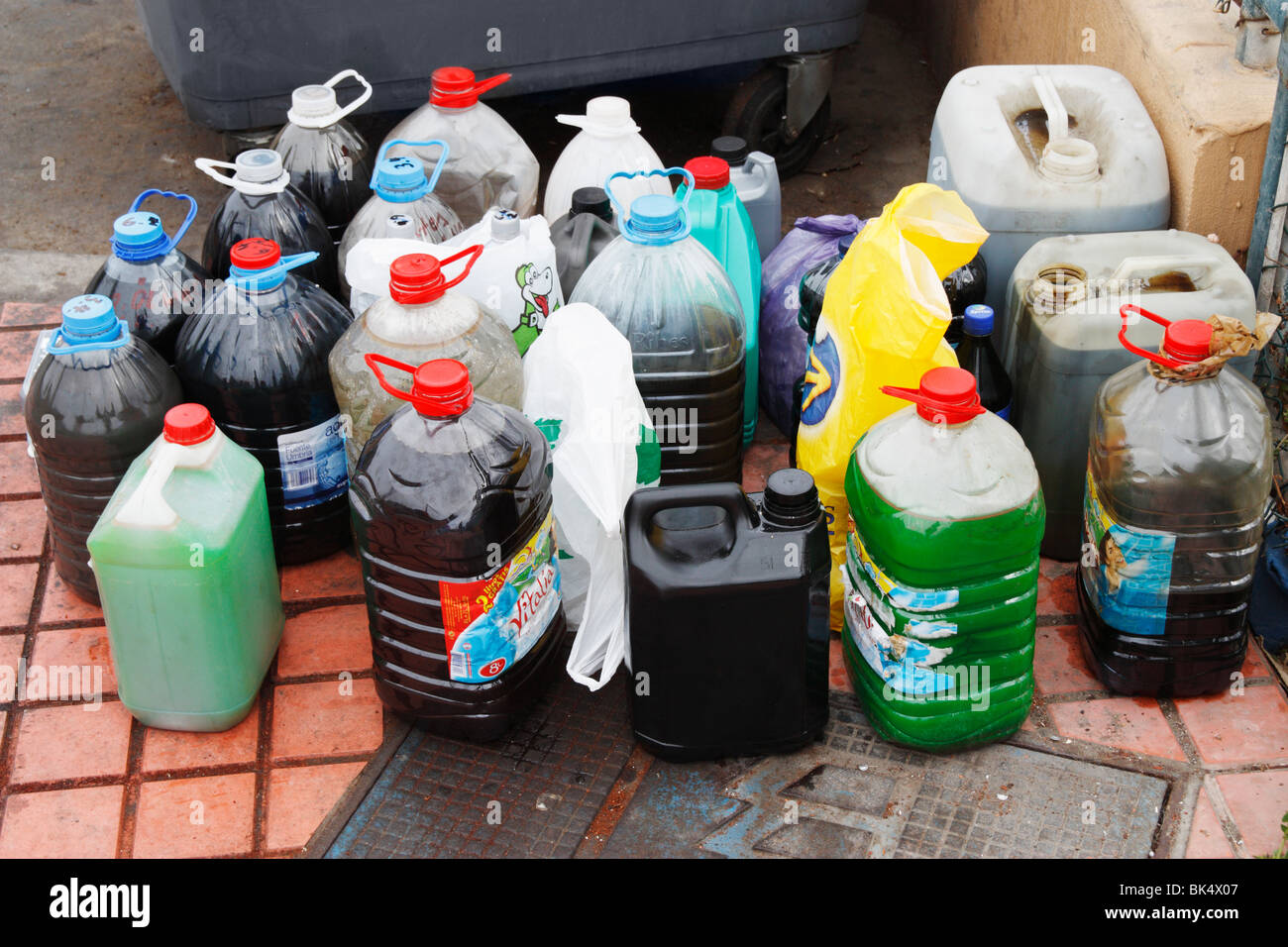 Containers of old engine oil and coolant next to oil recytcling tank in marina in Spain Stock Photo