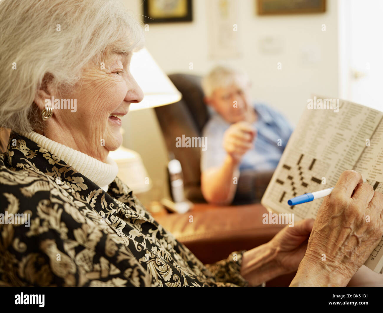 Elderly Couple in Retirement Home, Woman Working on Crossword Puzzle Stock Photo