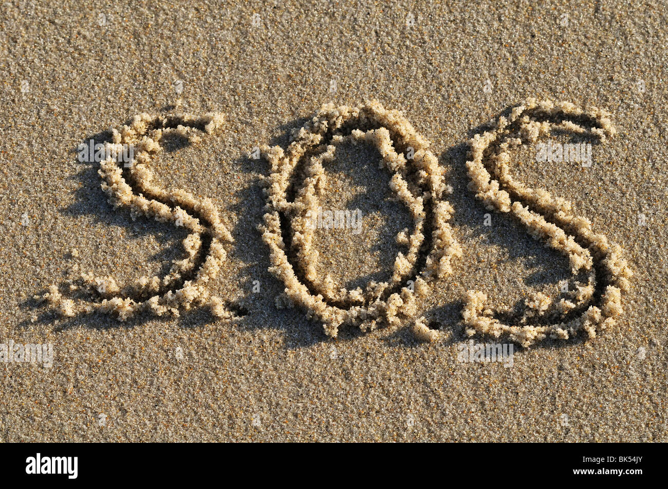 SOS Written in Sand Stock Photo