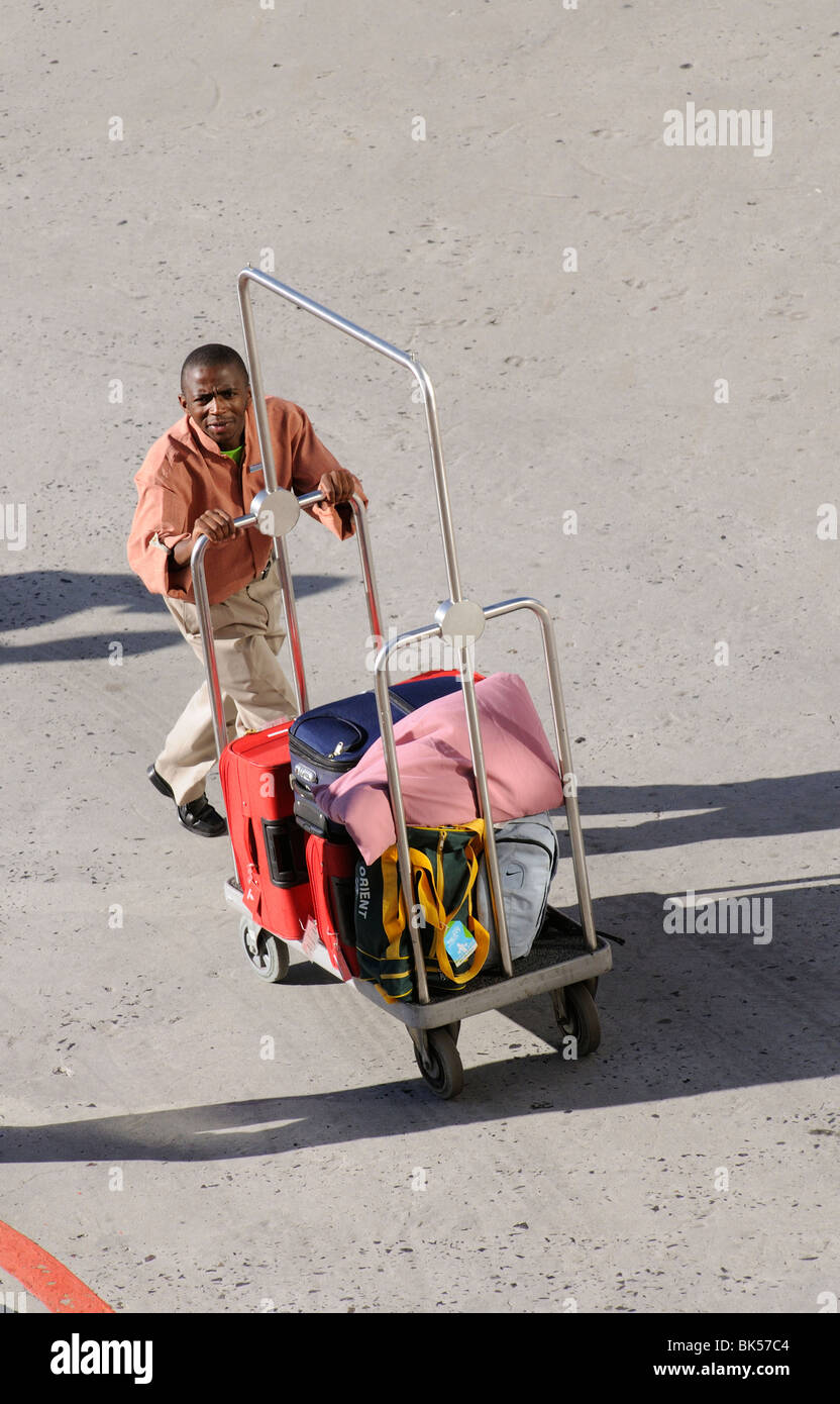 hotel bellboy pushing a guests luggage on his trolley Stock Photo - Alamy