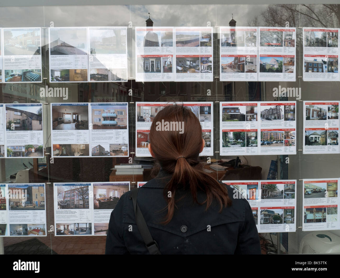 Woman looking at houses for sale in estate agents window in Utrecht The Netherlands Stock Photo