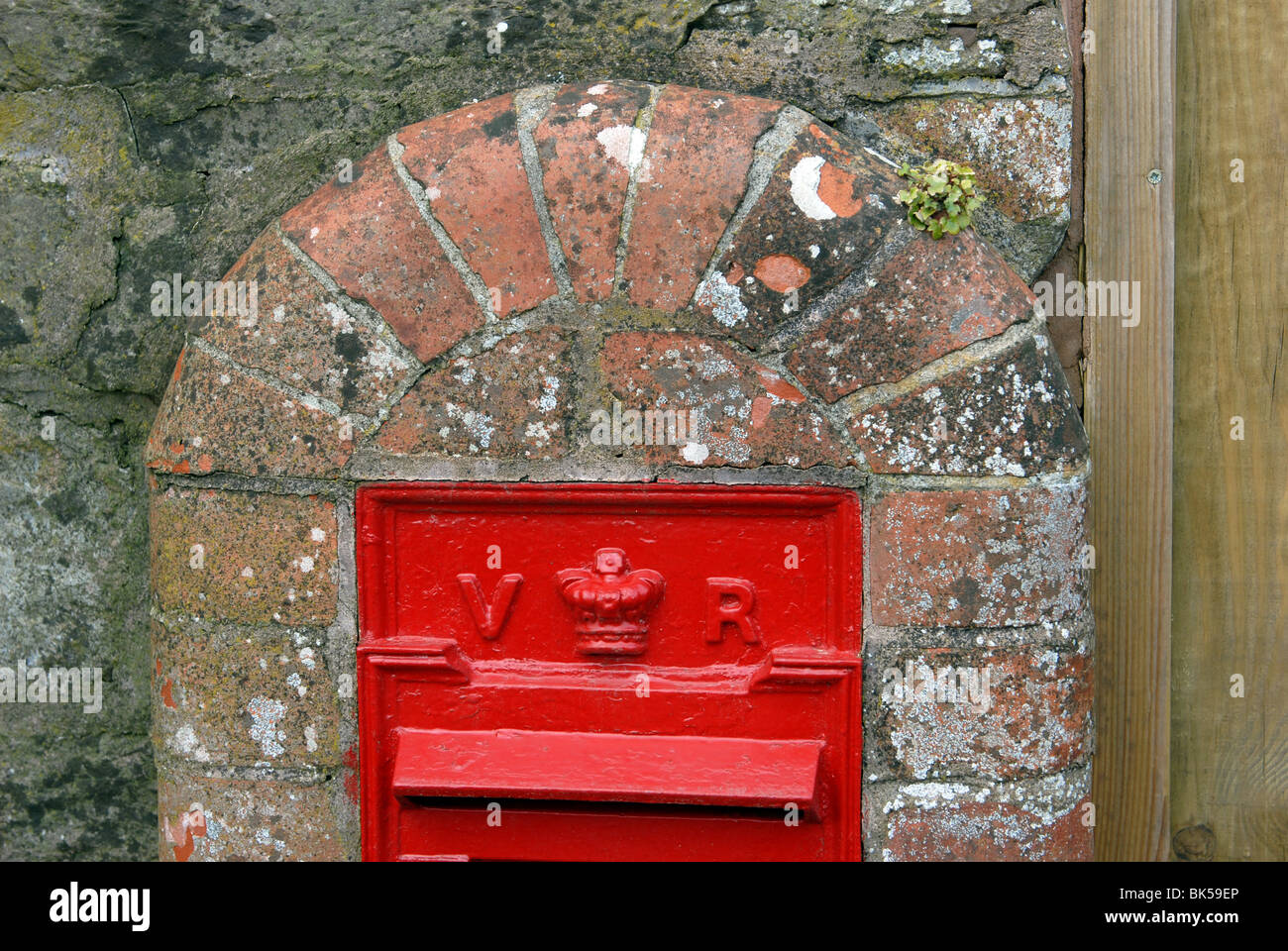 Bright red Victorian post box inserted into a brick pillar Stock Photo