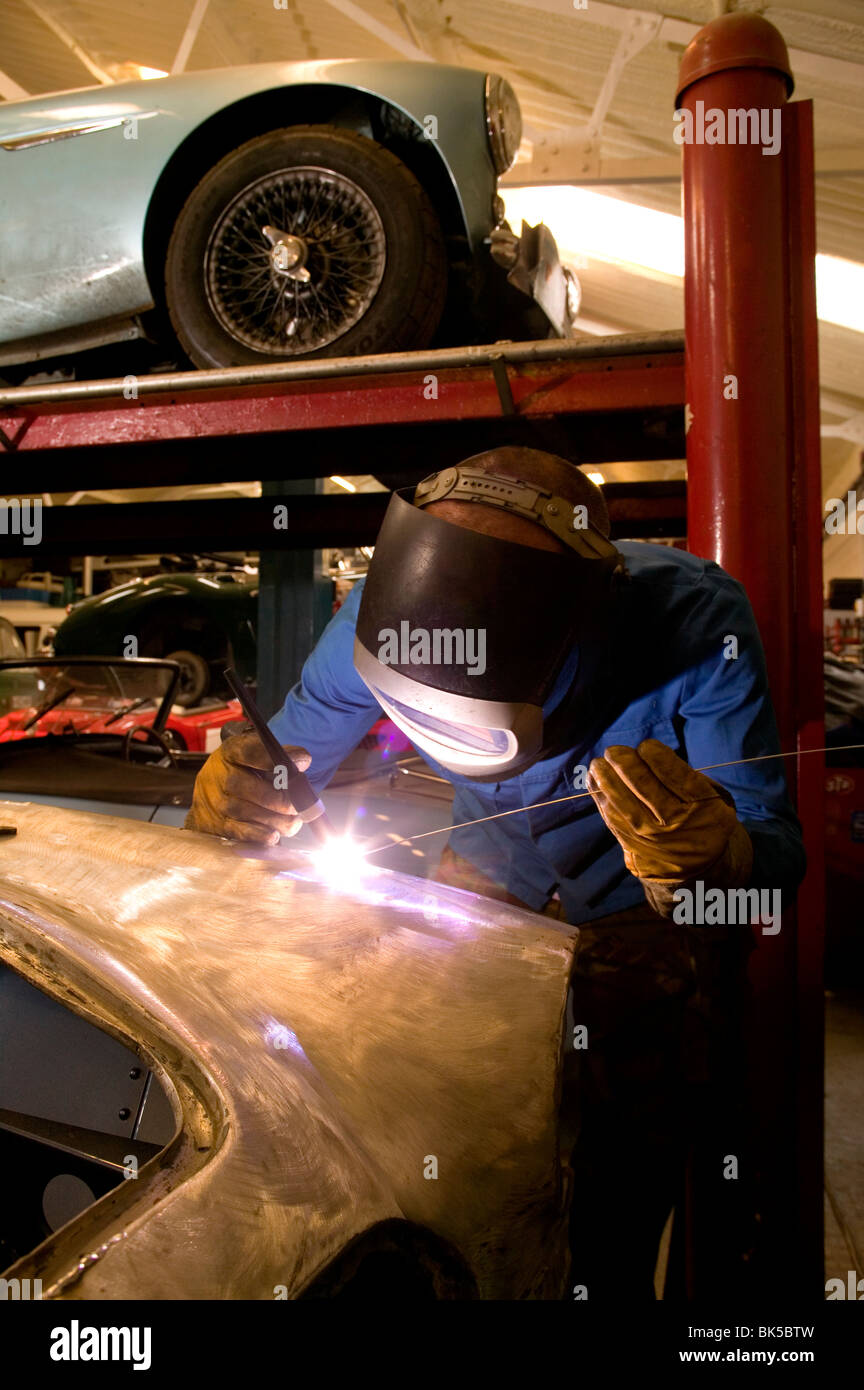 Welder working in Classic car restoration shop. Stock Photo