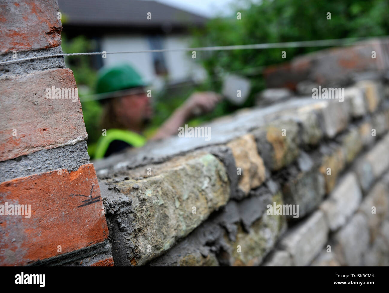 Building of a garden wall with Cotswold stone and reclaimed red bricks