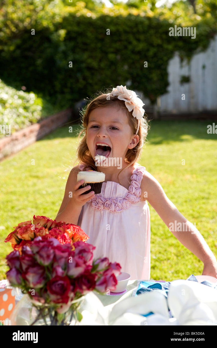 Girl licking frosting off cupcake Stock Photo Alamy