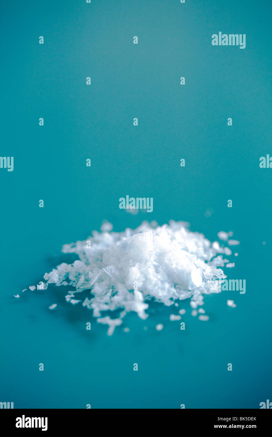 Sea salt flakes in a small pile on a glass table showing the detail of the flake of salt Stock Photo