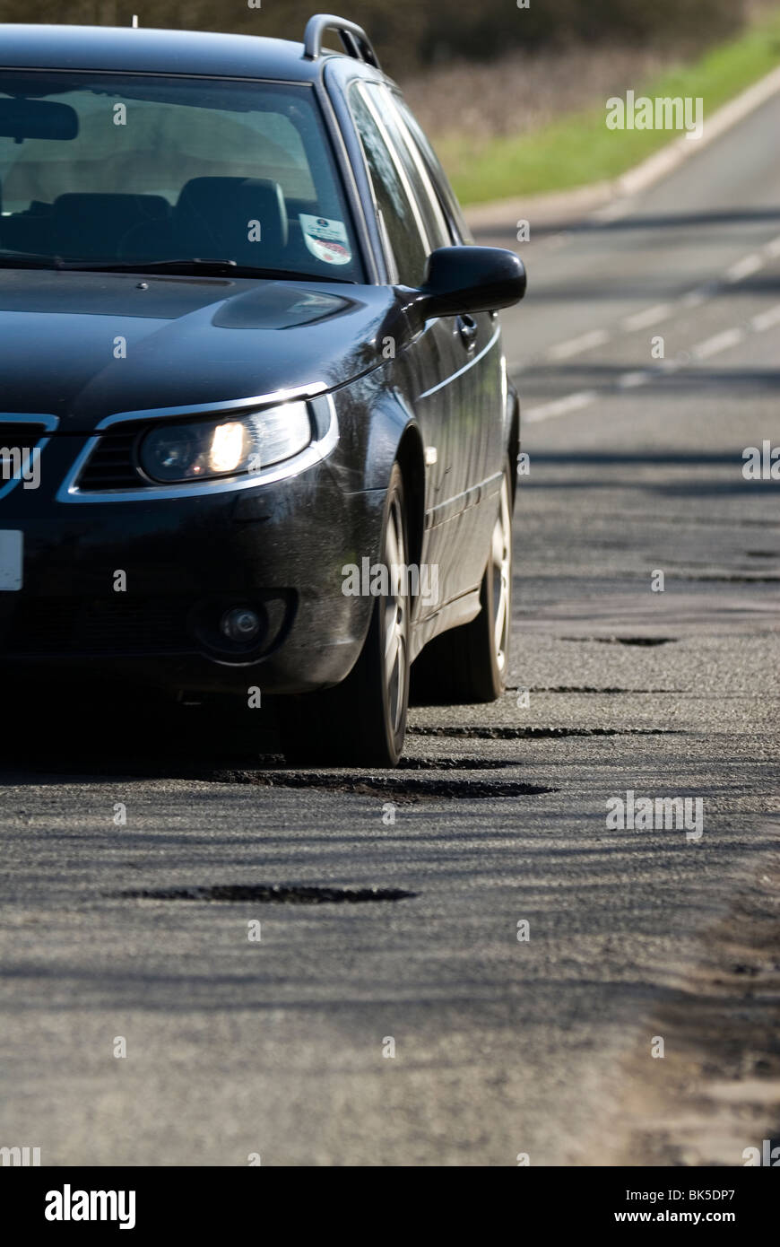 potholes in the middle of the road after a hard winter of snow. Who will pay for these pot holes to be repaired? Stock Photo