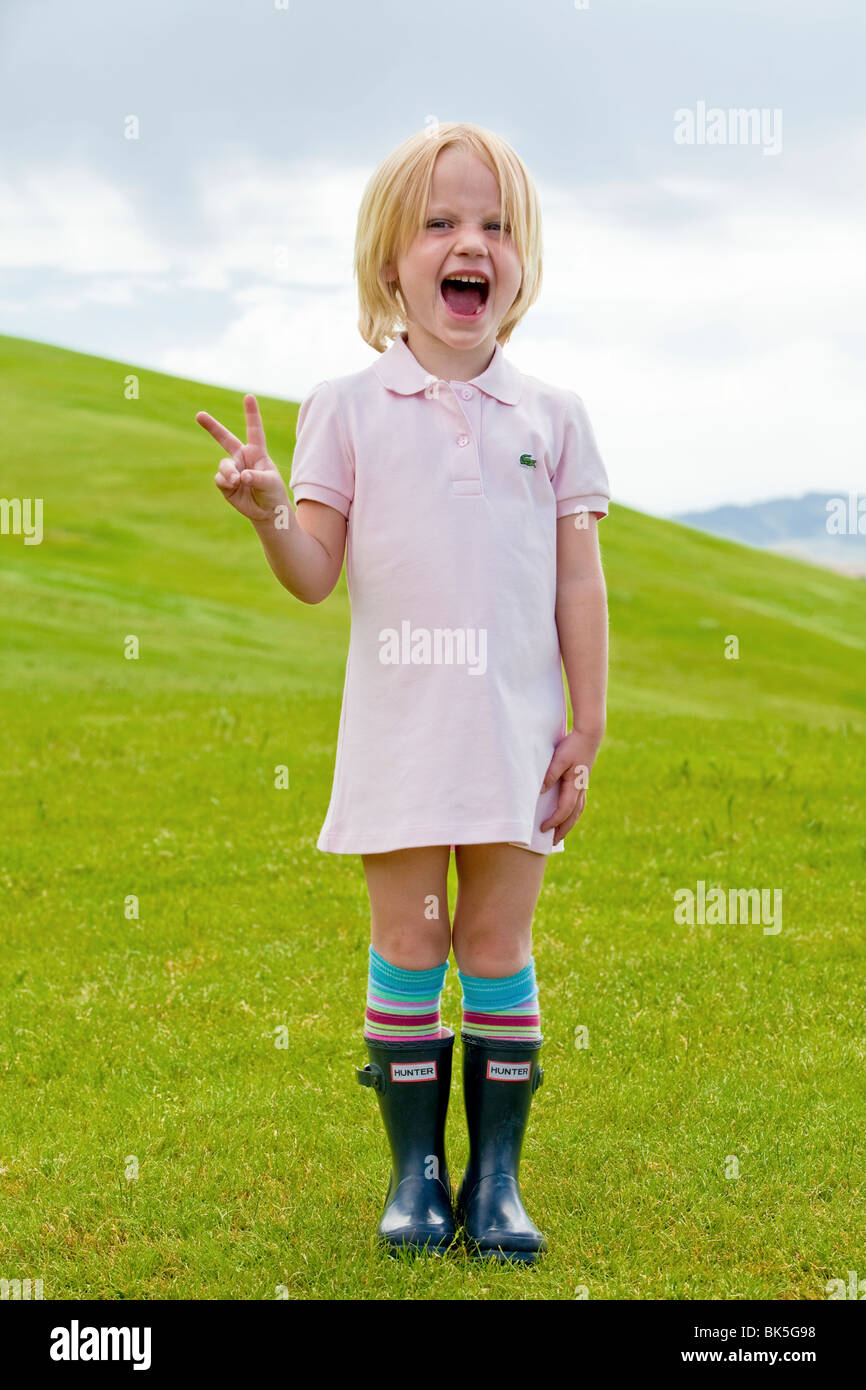Girl in polo dress and galoshes on hillside Stock Photo