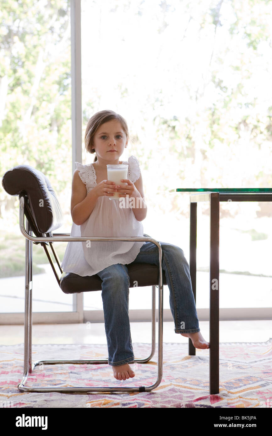 Young girl sitting in modern chair with glass of milk Stock Photo