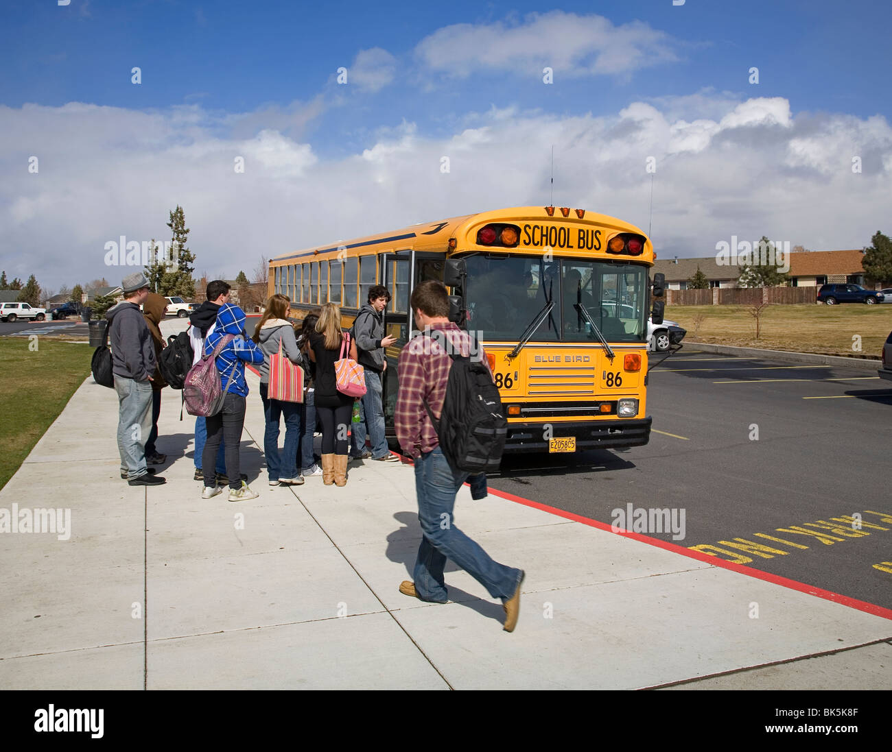 High school students board a school bus for the afternoon trip home after school Stock Photo