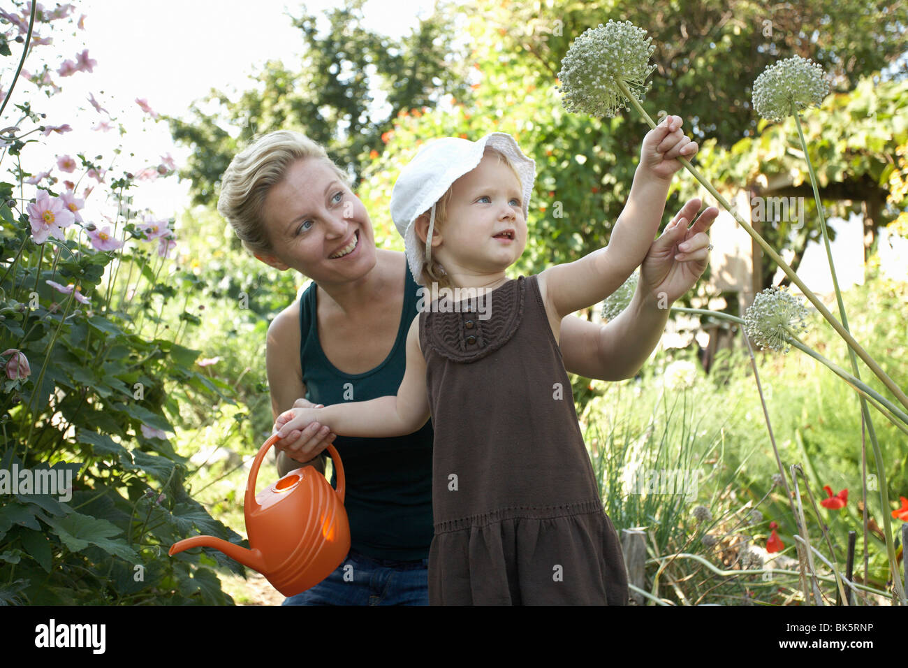 Mother and Daughter in Garden Watering Plants Stock Photo