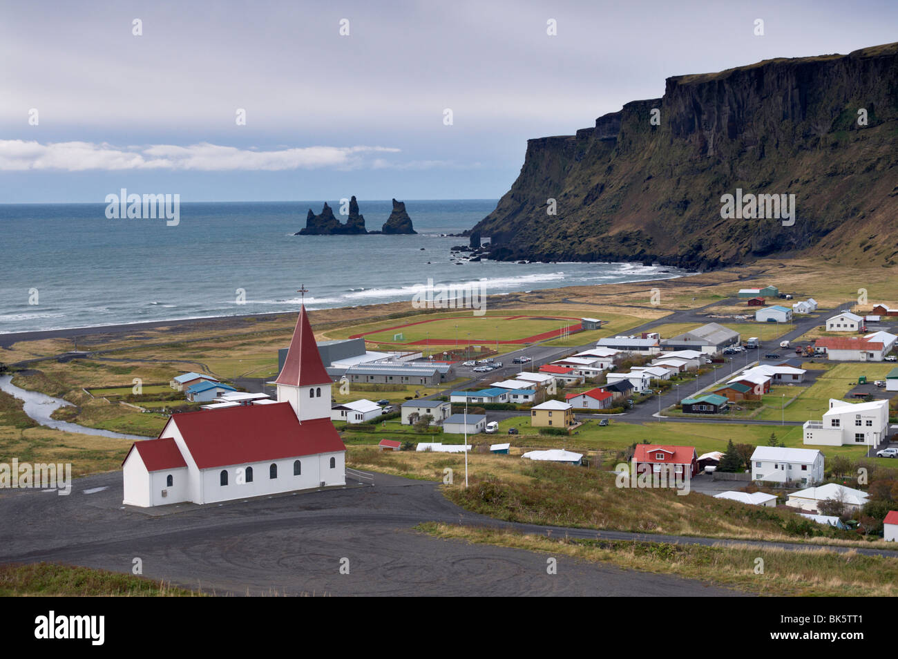 Church, village of Vik (Vik a Myrdal) and Reynisdrangar sea stacks in the distance, Iceland, Polar Regions Stock Photo