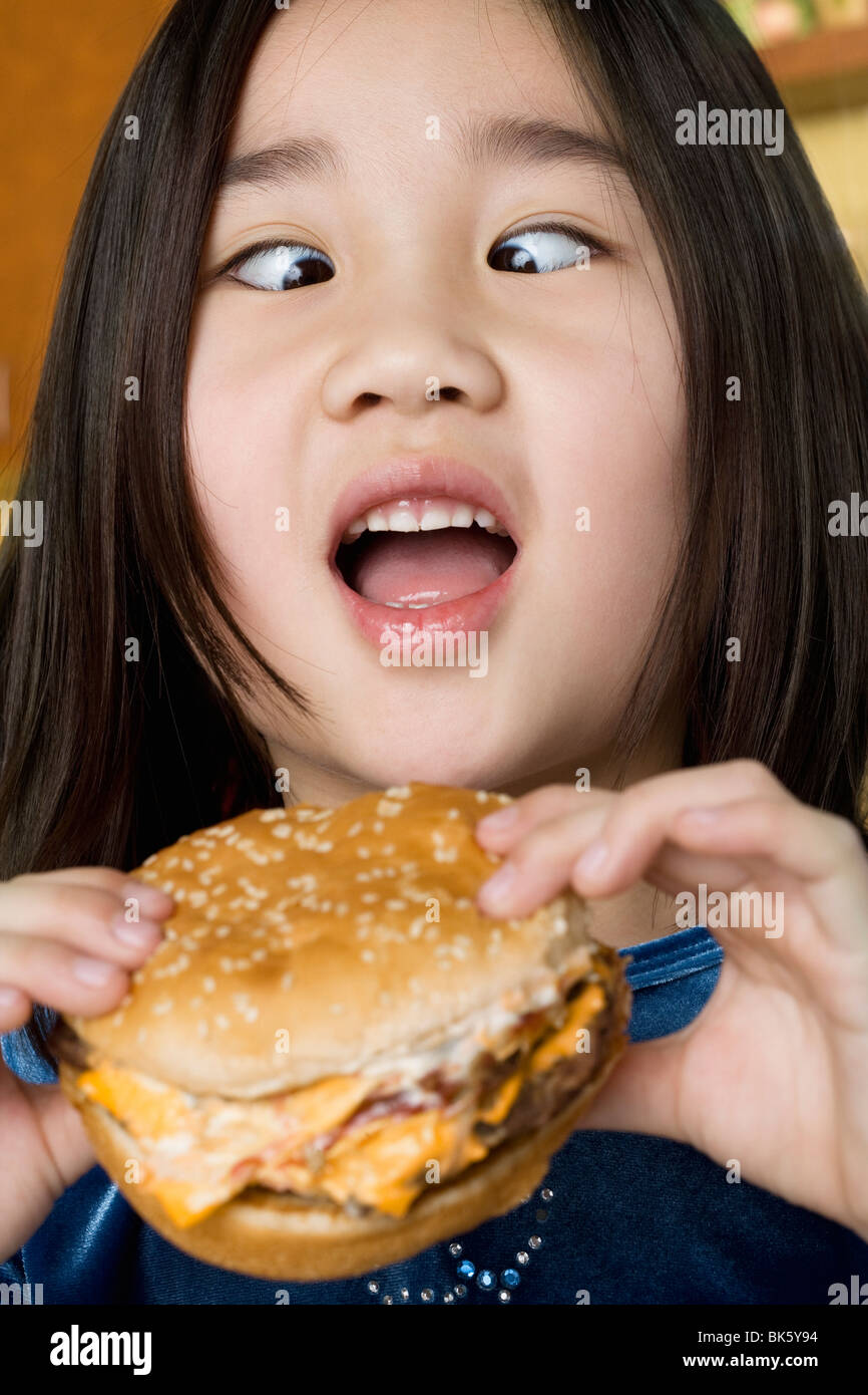 Crosseyed girl holding a burger Stock Photo Alamy
