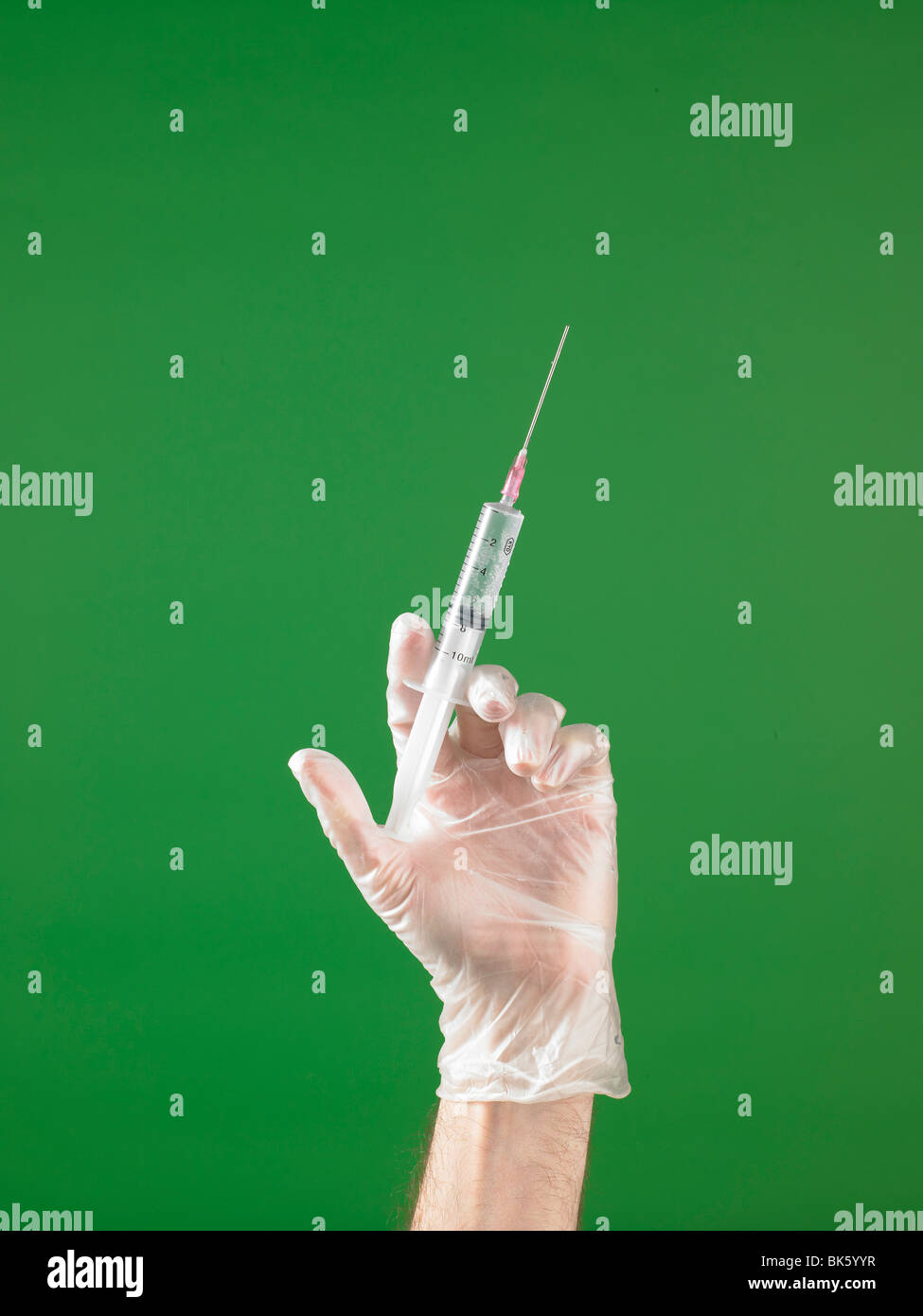 Medical gloved hand with syringe and needle with a liquid drop Stock