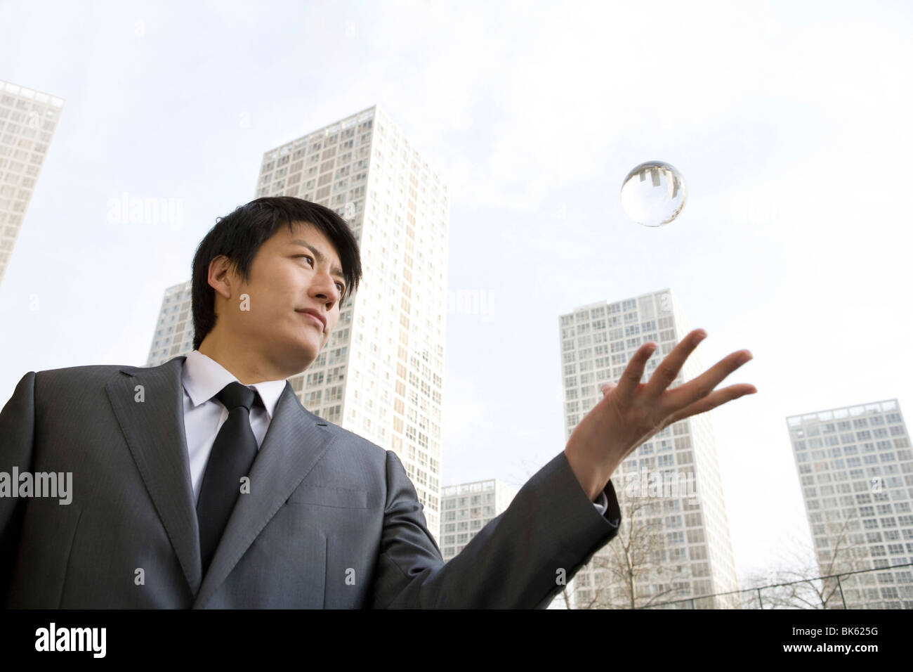Businessman throwing crystal ball in mid-air Stock Photo - Alamy