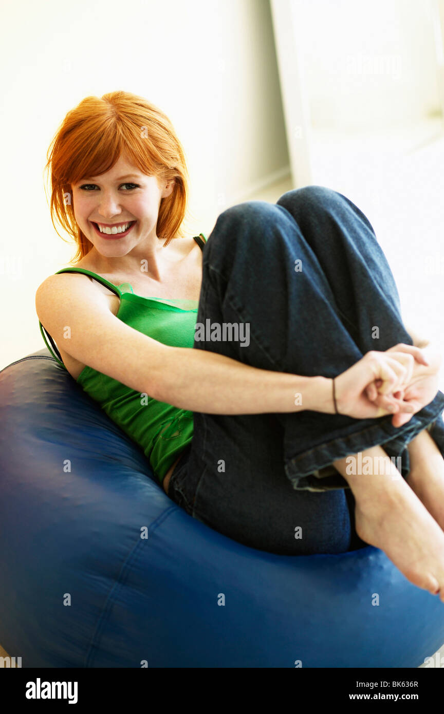 Young woman reclining on a bean bag and smiling Stock Photo - Alamy