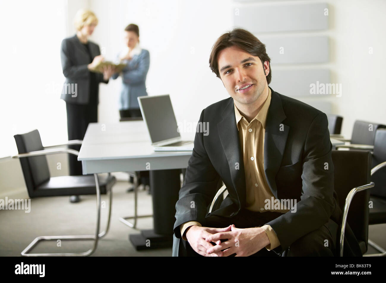 Portrait of a businessman smiling with his colleague working in the background Stock Photo