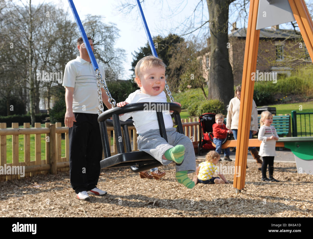 Baby boy on swing in childrens play area playground in Telford Uk Stock Photo