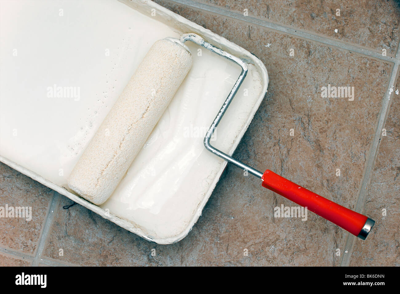 a used paint roller is sitting in pan with paint on floor Stock Photo ...