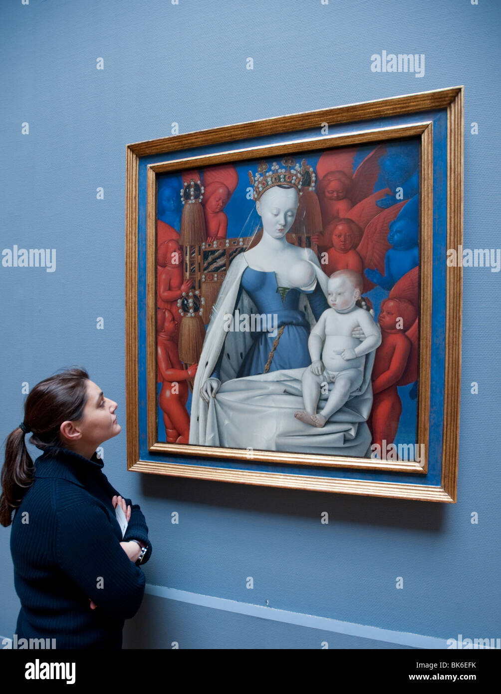visitor looking at painting of Mary and Jesus surrounded by Seraphim and Cherubs by Jean Fouquet at Royal Museum of Fine Arts in Stock Photo