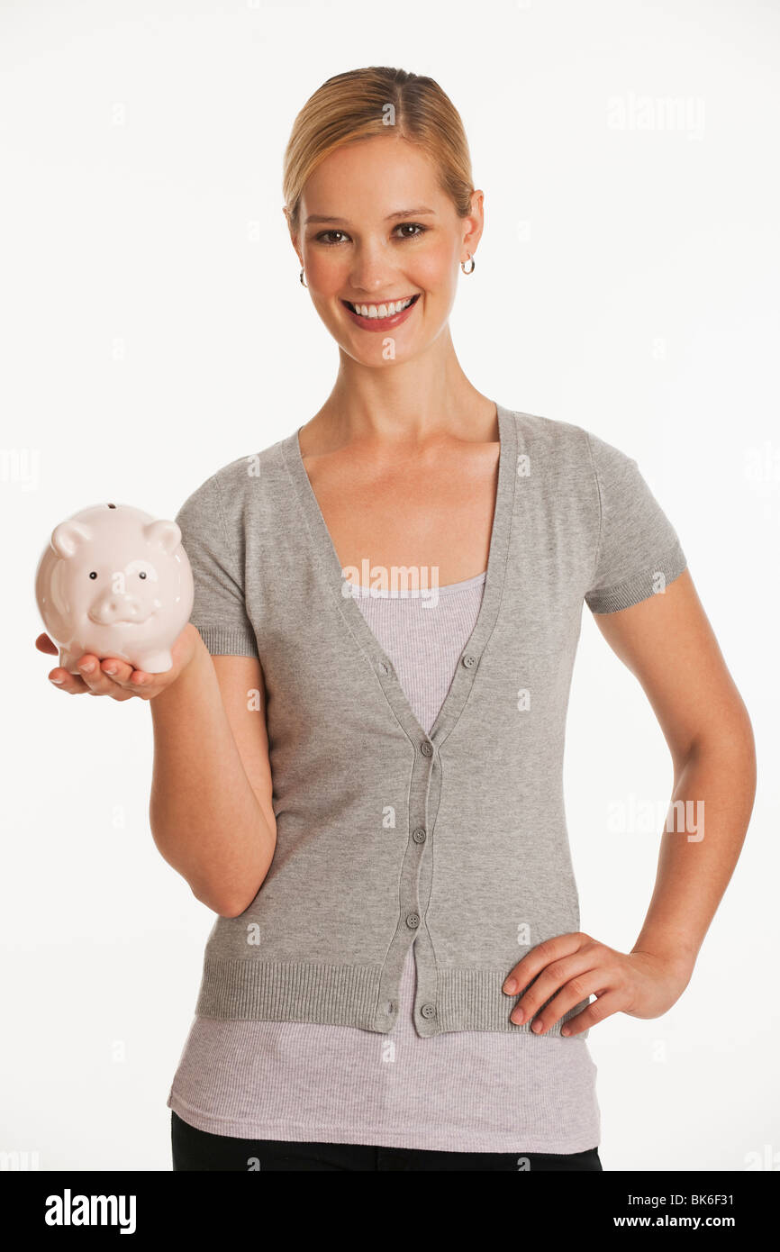 young woman holding up piggy bank on white seamless background Stock Photo