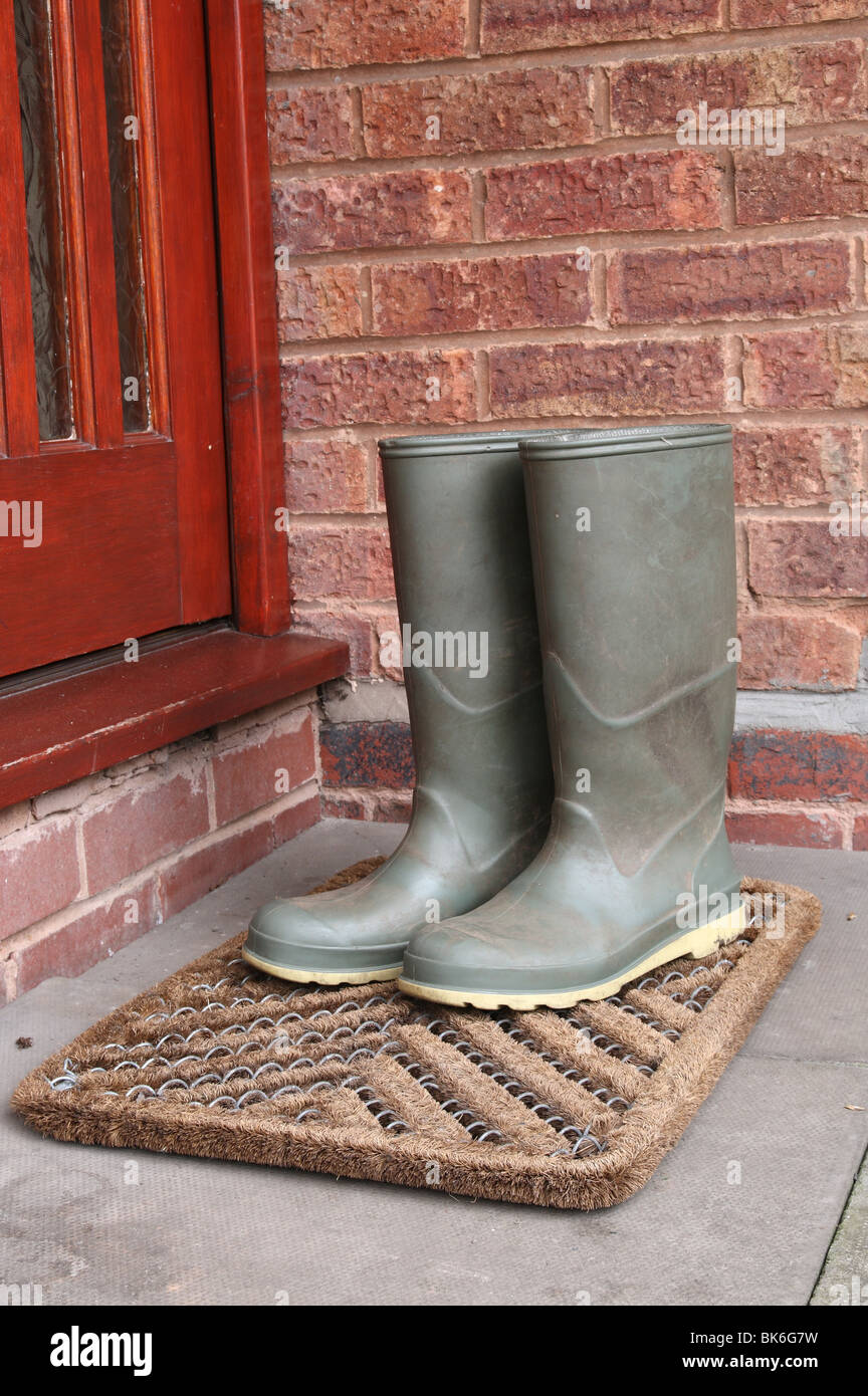Green Wellington Boots on Door Mat by Front Door Outside Stock Photo