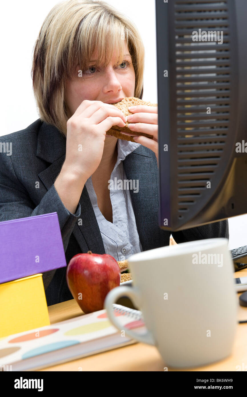 female office worker eating working lunch Stock Photo - Alamy