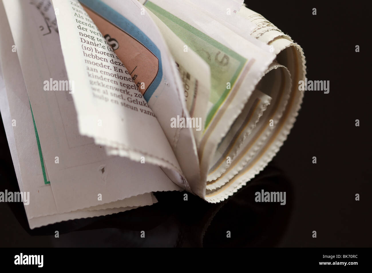 rolled up newspaper with rubber band on black Stock Photo Alamy