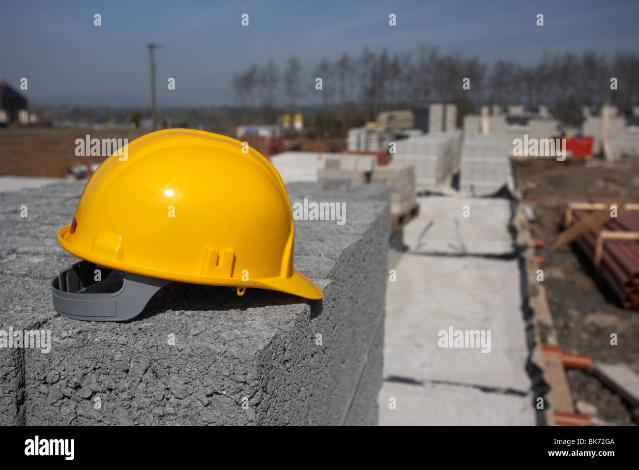 hard hat sitting on a pile of breeze concrete building blocks on stopped construction building site in northern ireland uk Stock Photo