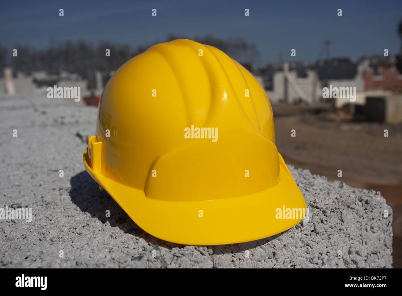 hard hat sitting on a pile of breeze concrete building blocks on an empty construction building site in northern ireland uk Stock Photo