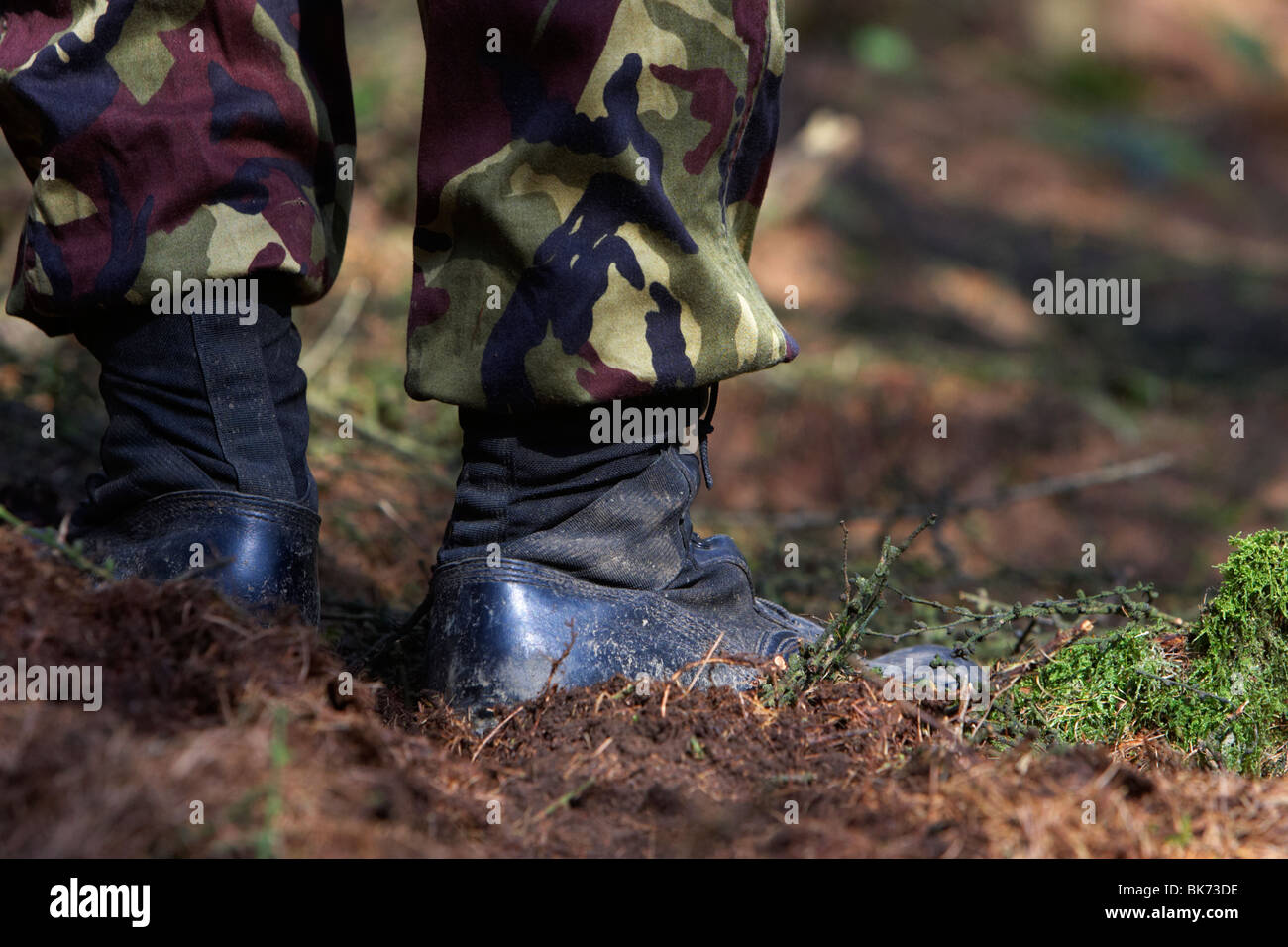 man wearing camouflage combat trousers and boots standing in a forest in the uk Stock Photo