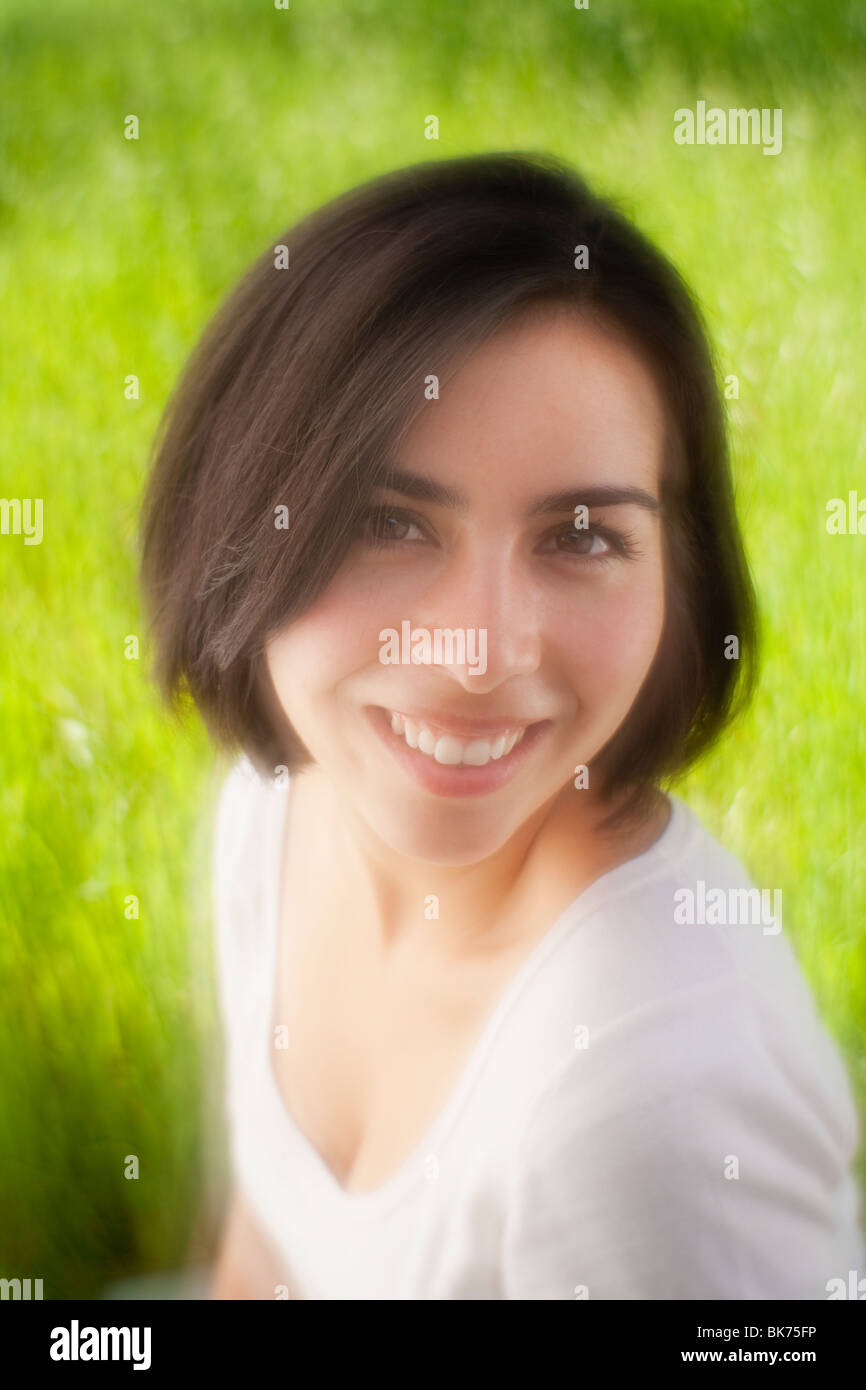 young Hispanic woman smiling in a grassy meadow, Lensbaby Soft Focus Optic Stock Photo