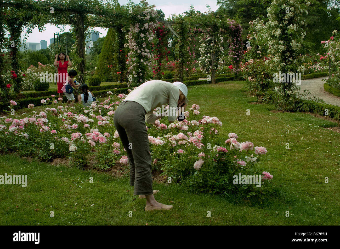 womann-in-garden-paris-france-bent-over-taking-photos-urban-park
