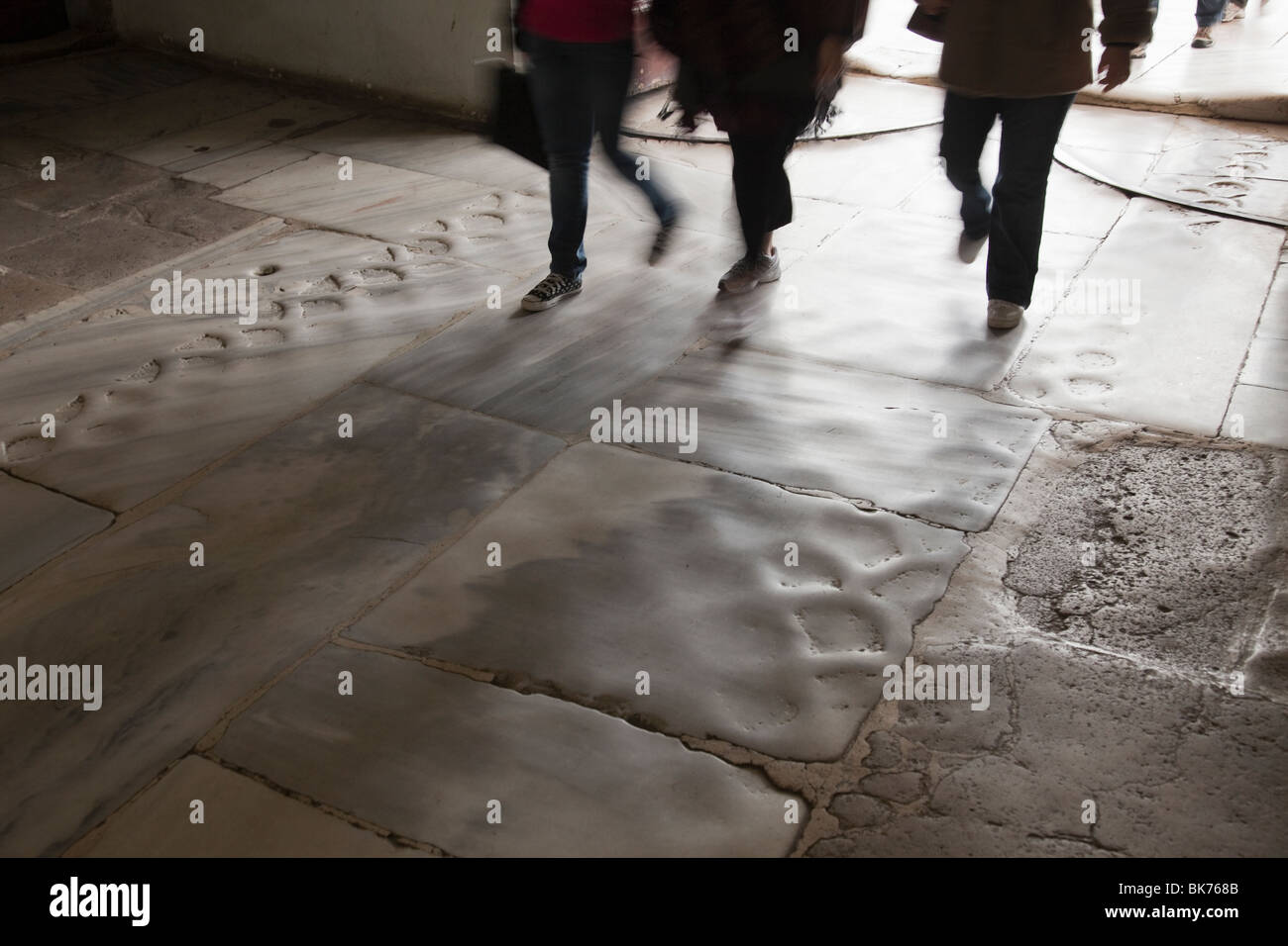 Blurred legs of tourists entering Topkapi Museum in Istanbul over marble entry worn down from millions of feet. Stock Photo
