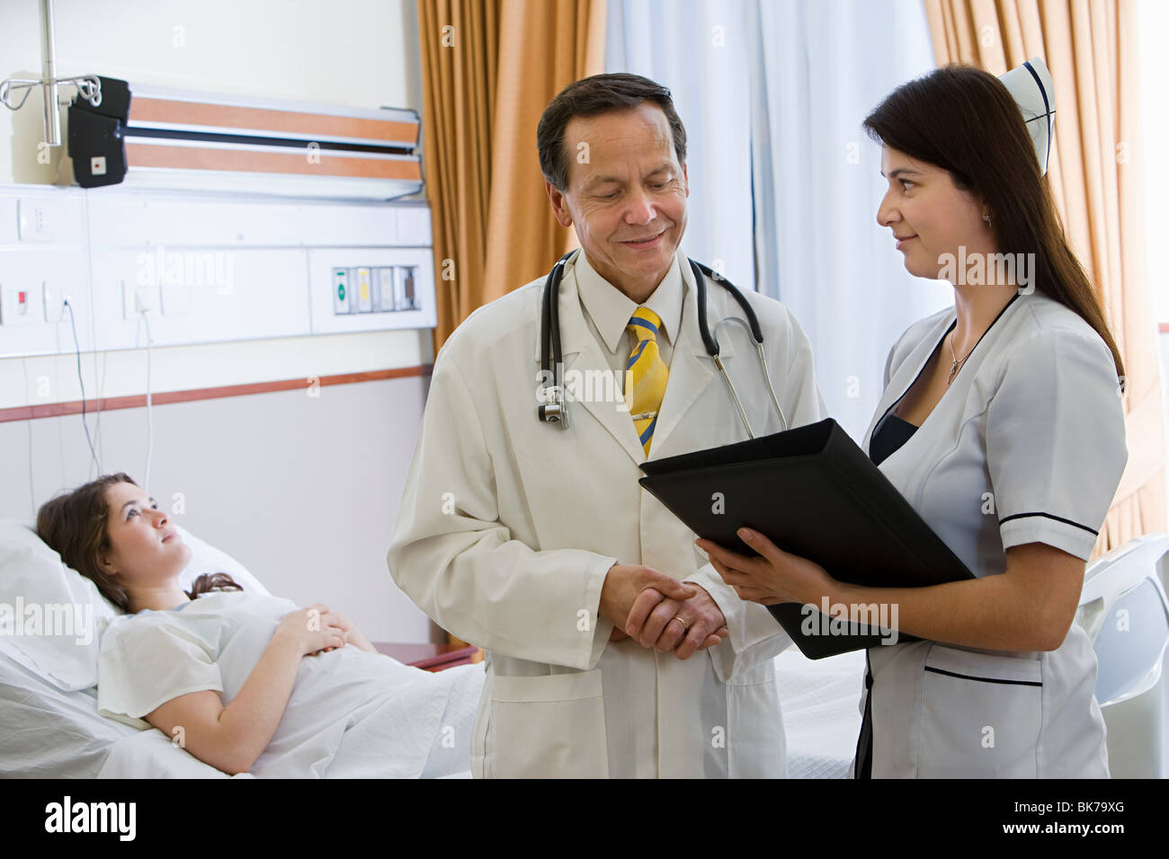 Young woman in hospital room with doctor and nurse Stock Photo